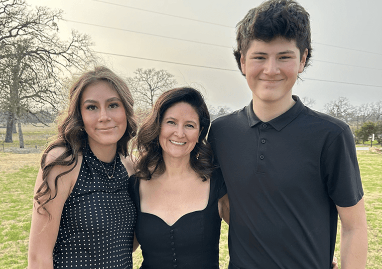Dr. Jennifer Leason standing between her son and daughter in a field. Everyone is wearing semi formal dress clothes.